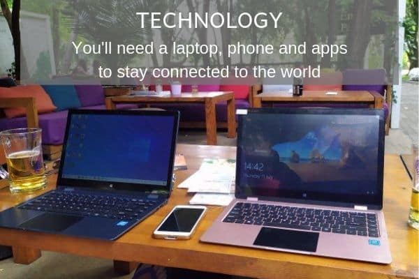Things to Consider as a Digital Nomad - Technology. 2 laptops and a phone on a table in an outdoor restarurant